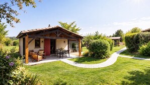 A rustic wooden house with a patio, surrounded by a well-maintained lawn and garden.