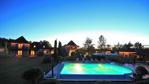 A large swimming pool surrounded by a well-maintained lawn and a variety of outdoor seating areas.