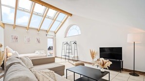 A modern living room with a large window, a sofa, a coffee table, a TV, and a lamp.