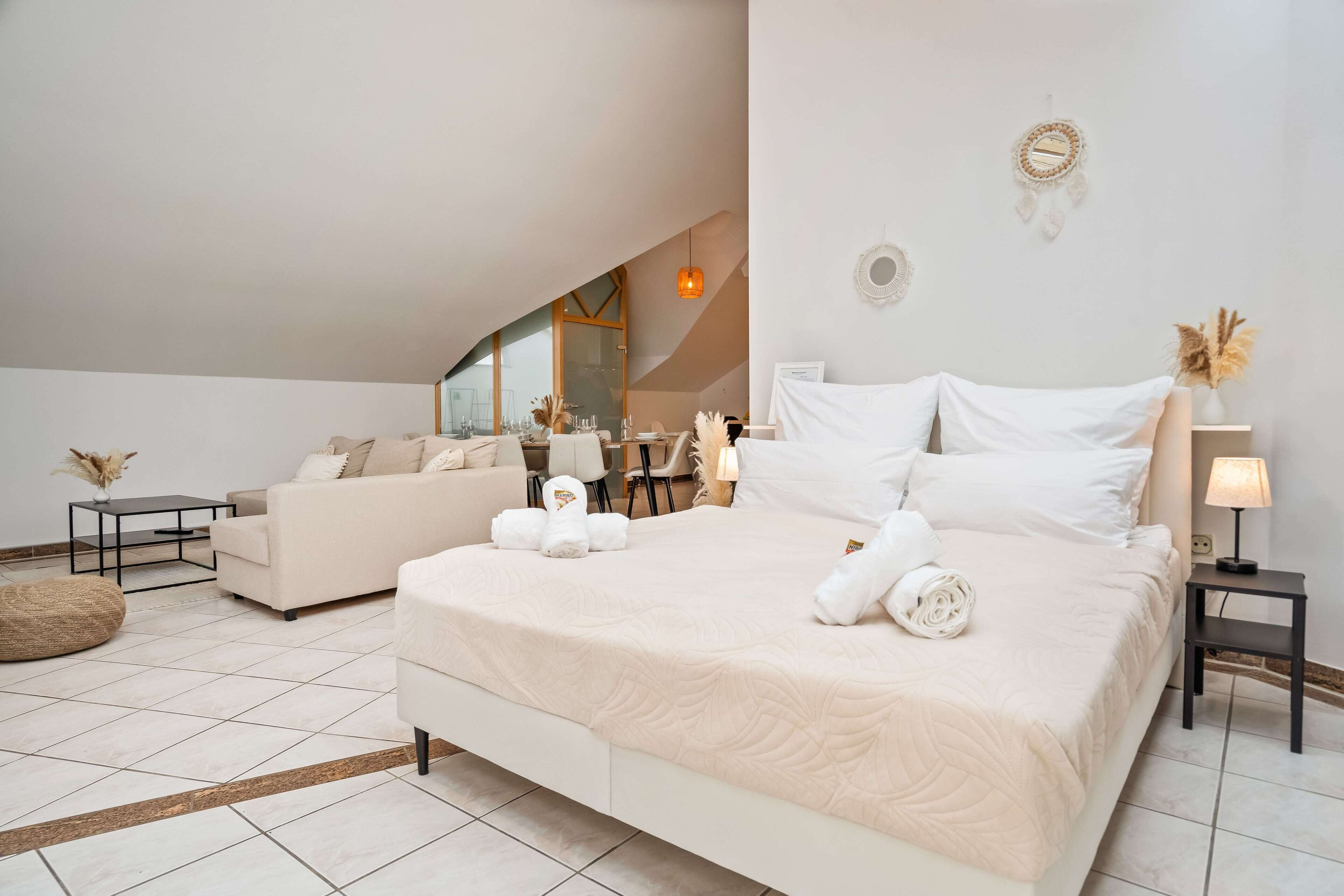 A modern bedroom with a large bed, a sofa, and a dining area.