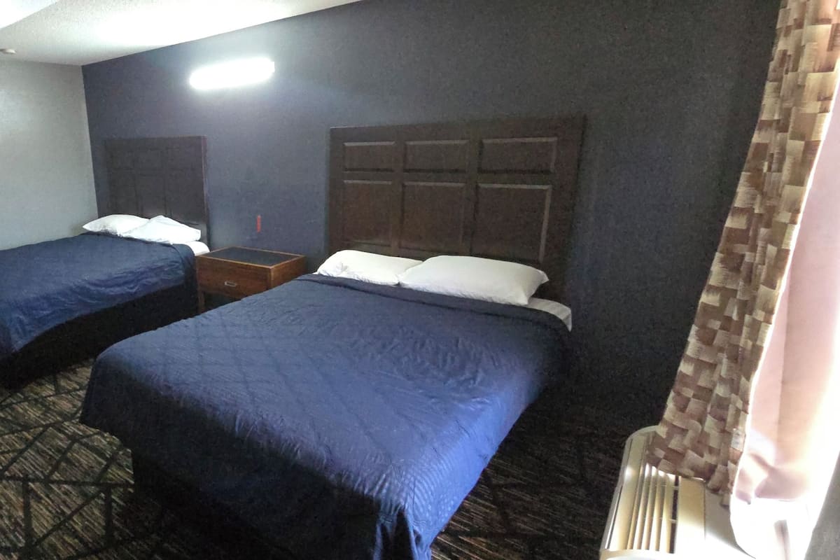 Ein Hotelzimmer mit zwei Betten, einem Schreibtisch, einem Spiegel und einem Fenster mit Vorhängen.