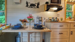 A kitchen with a wooden table, a microwave, a coffee maker, and a sign indicating a coffee station.