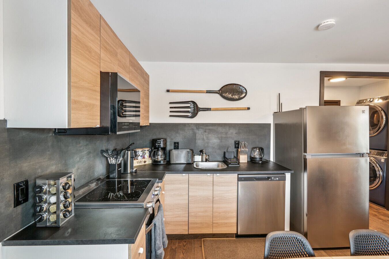 A modern kitchen with wooden cabinets, a stainless steel refrigerator, a dishwasher, and a coffee maker.