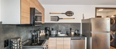 A modern kitchen with wooden cabinets, a stainless steel refrigerator, a dishwasher, and a coffee maker.