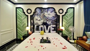 A hotel room with a bed, a wall mural, and a decorative 'LOVE' balloon arrangement.