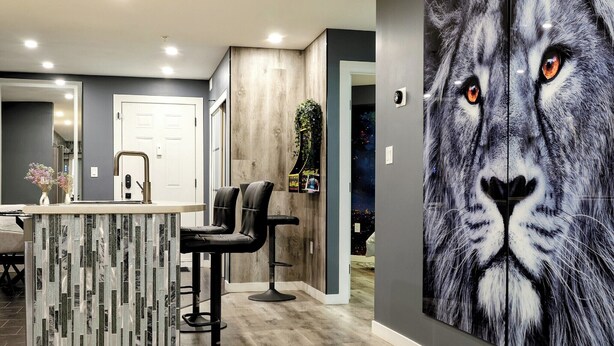 A modern interior with a bar area, seating, and a large wall mural. - Modern 2BR Condo with secure parking and walking distance to Rogers Place  (Edmonton)