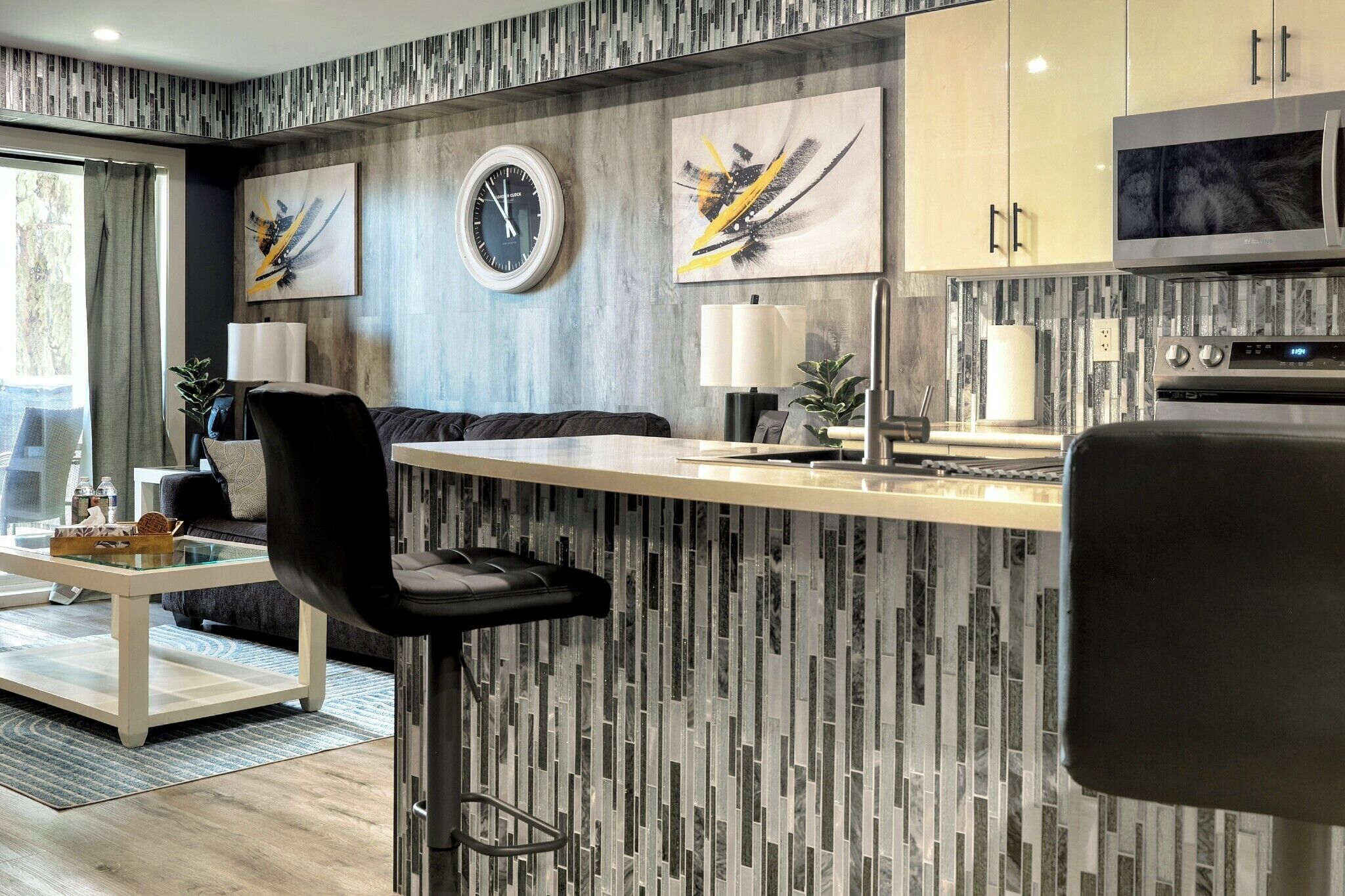 Une cuisine moderne avec un coin bar, une table à manger avec des chaises et un espace salon comprenant un canapé et une table basse.