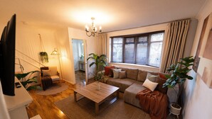 A cozy living room with a sofa, coffee table, and potted plants.