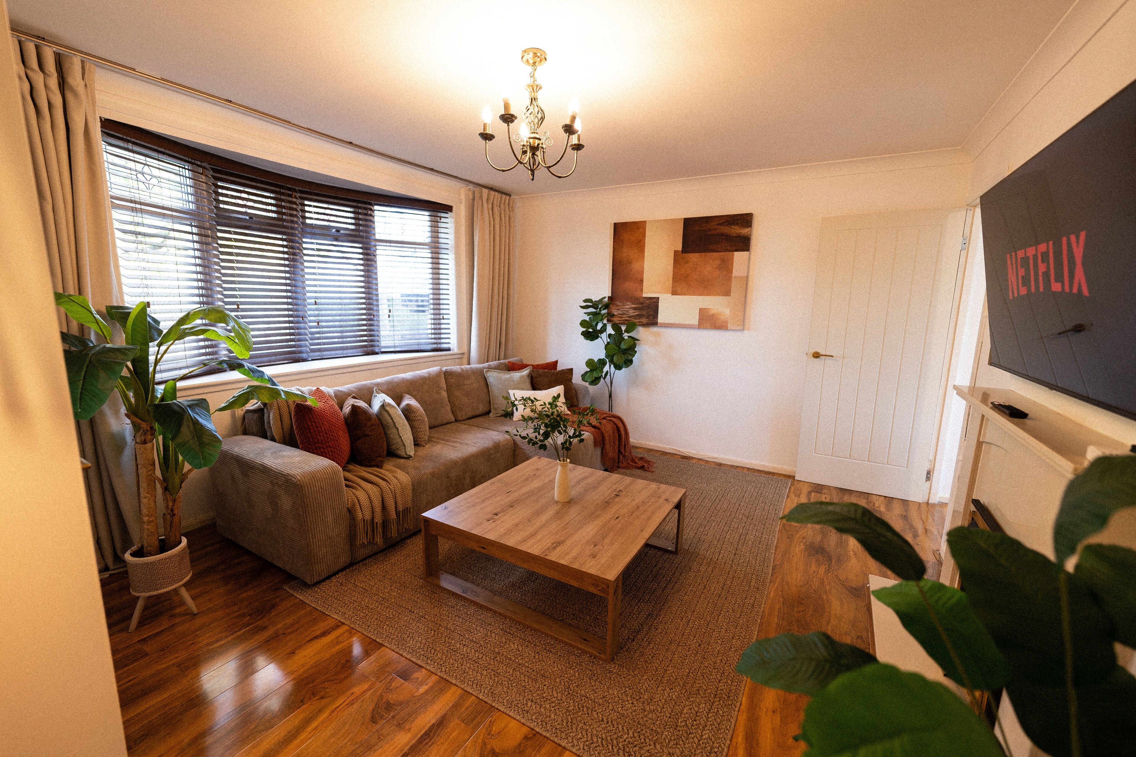 A living room with a sofa, coffee table, and potted plants.