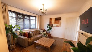 A living room with a sofa, coffee table, and potted plants.
