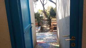 A blue door leading to a tiled patio with a tree and outdoor furniture. - Beachfront villa, right ON SAND! (Cala Liberotto)