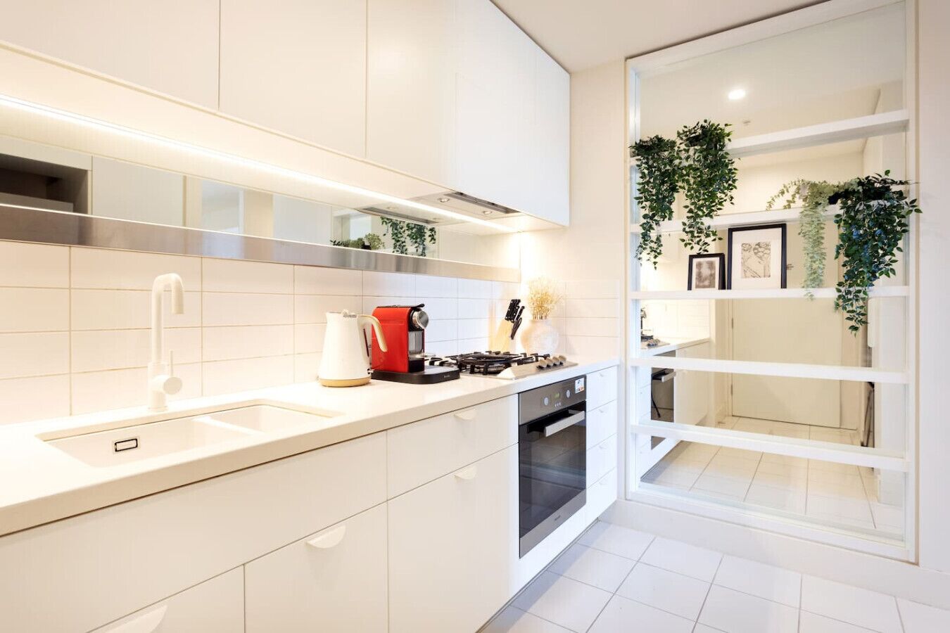 A modern kitchen with white cabinetry, a built-in oven, and a stainless steel range hood.