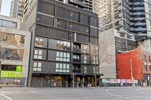 A multi-story building with a modern architectural design, featuring large windows and a prominent entrance. - Oaks Opus | 1BR Southbank Gem (Southbank)
