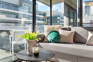 A modern living room with a sofa, pillows, a small table, and a potted plant.