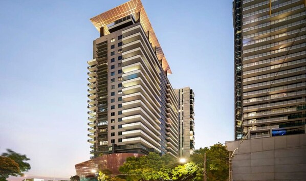 Un edificio moderno di grandi dimensioni con un design distintivo a tetto inclinato e numerosi balconi.