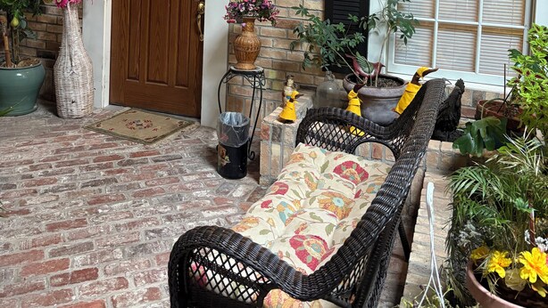 A brick building with a wooden door, a bench, and potted plants. - #10 Apartment with southwestern vibes. (Lorain)
