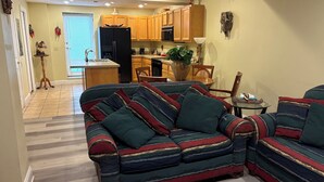 A living room with a striped sofa, wooden cabinets, and a kitchen area in the background. - #10 Apartment with southwestern vibes. (Lorain)