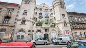Un bâtiment historique doté d’une tour centrale, de nombreux balcons et d’une entrée située au niveau du sol.
