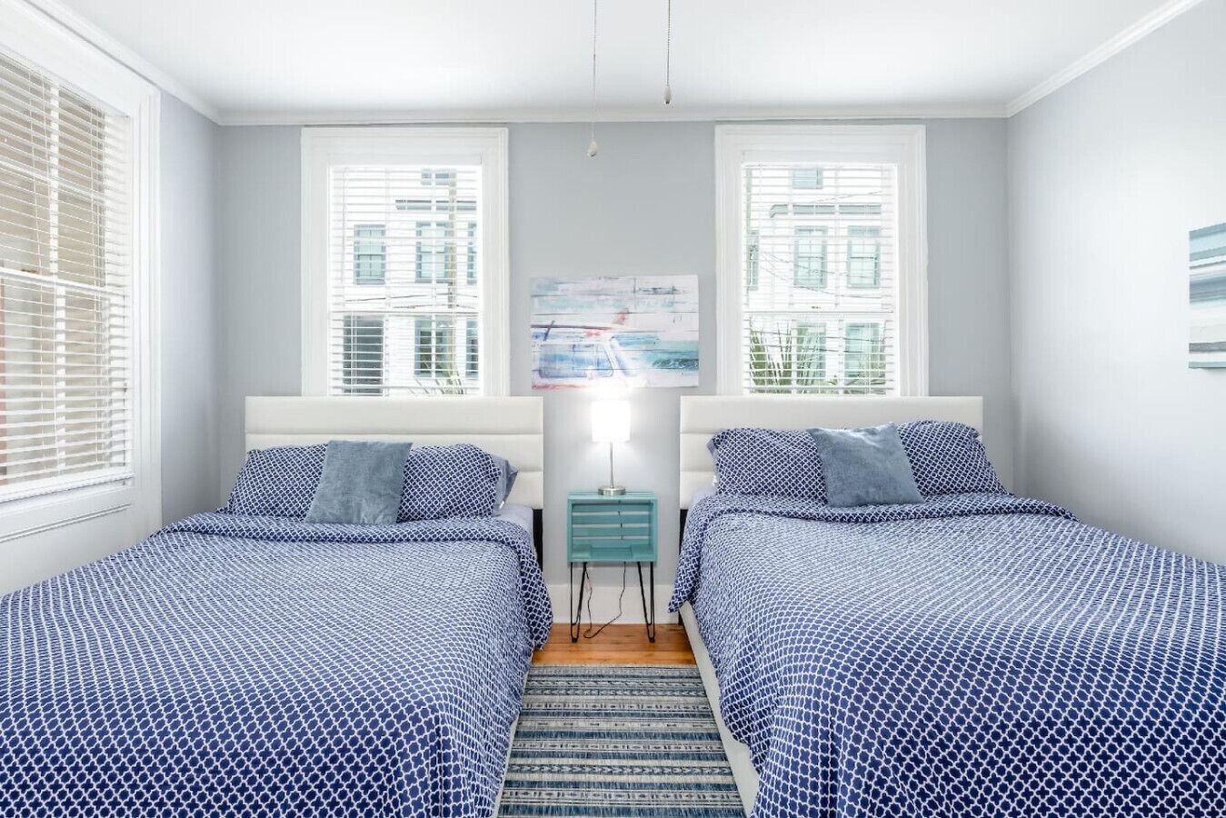 Ein Schlafzimmer mit zwei Betten, einem Nachttisch, einer Lampe und einem Bild an der Wand.