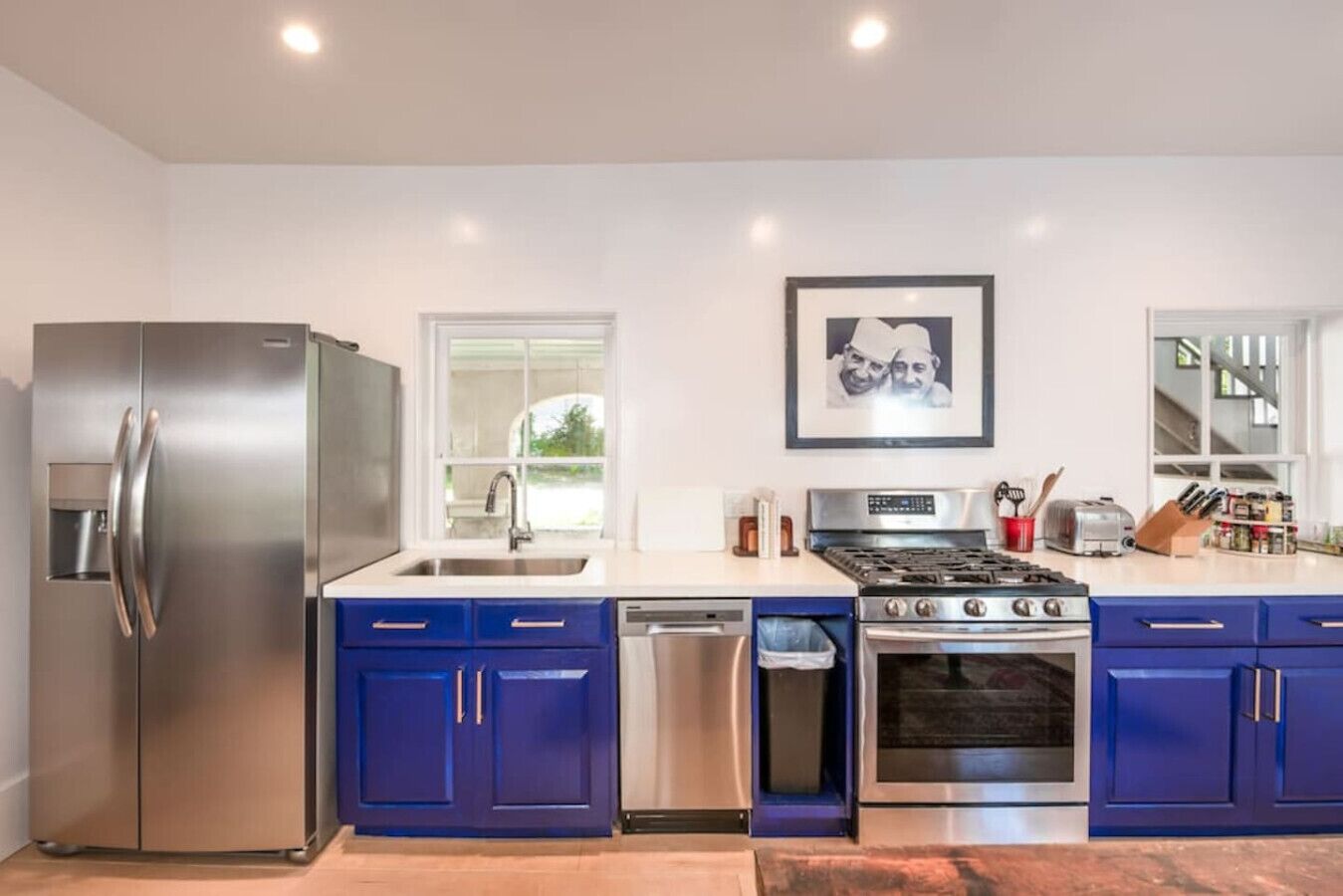 Una cocina moderna con electrodomésticos de acero inoxidable, armarios azules, lavavajillas y cocina a gas.