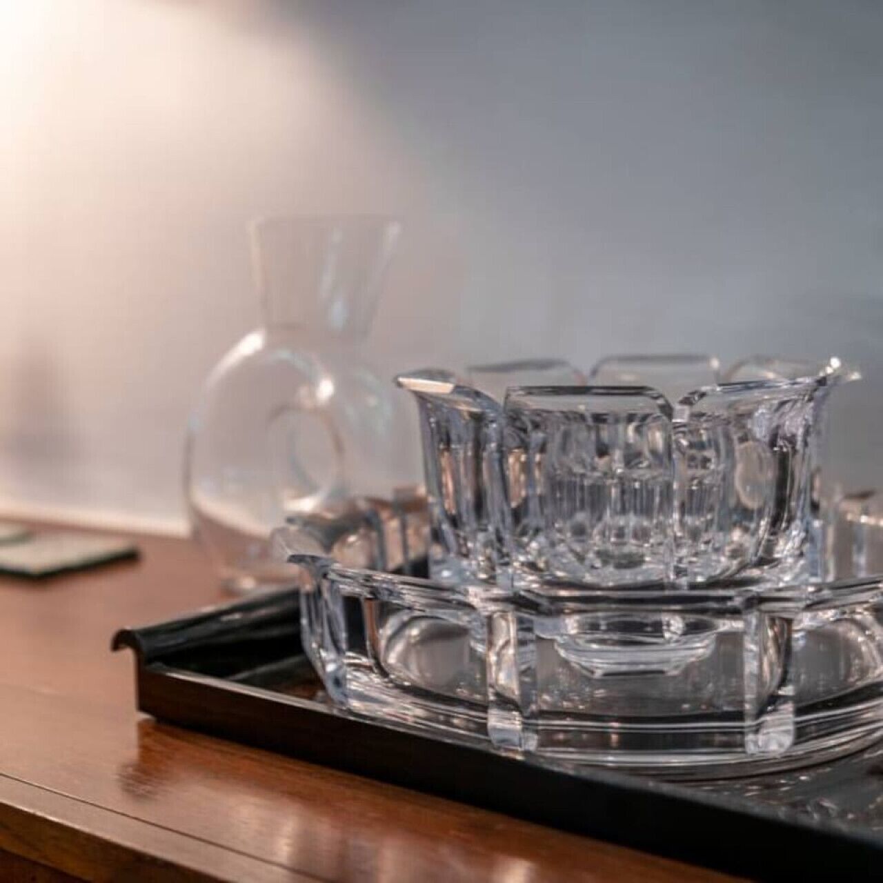 Un plateau surmonté de verres transparents, posé sur une surface en bois.