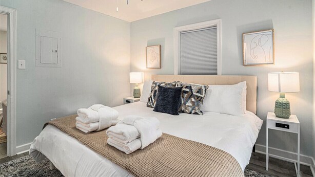 A bedroom with a bed, two bedside tables, a ceiling fan, and artwork on the walls.