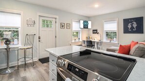 A modern kitchen with a built-in stove, a dining area with a table and chairs, and a seating area with a sofa.