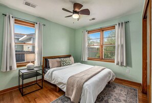 A bedroom with a bed, a nightstand, a ceiling fan, and two windows with curtains. - Waylyn Chic~Very Convenient Location, Pool Table! (North Charleston)