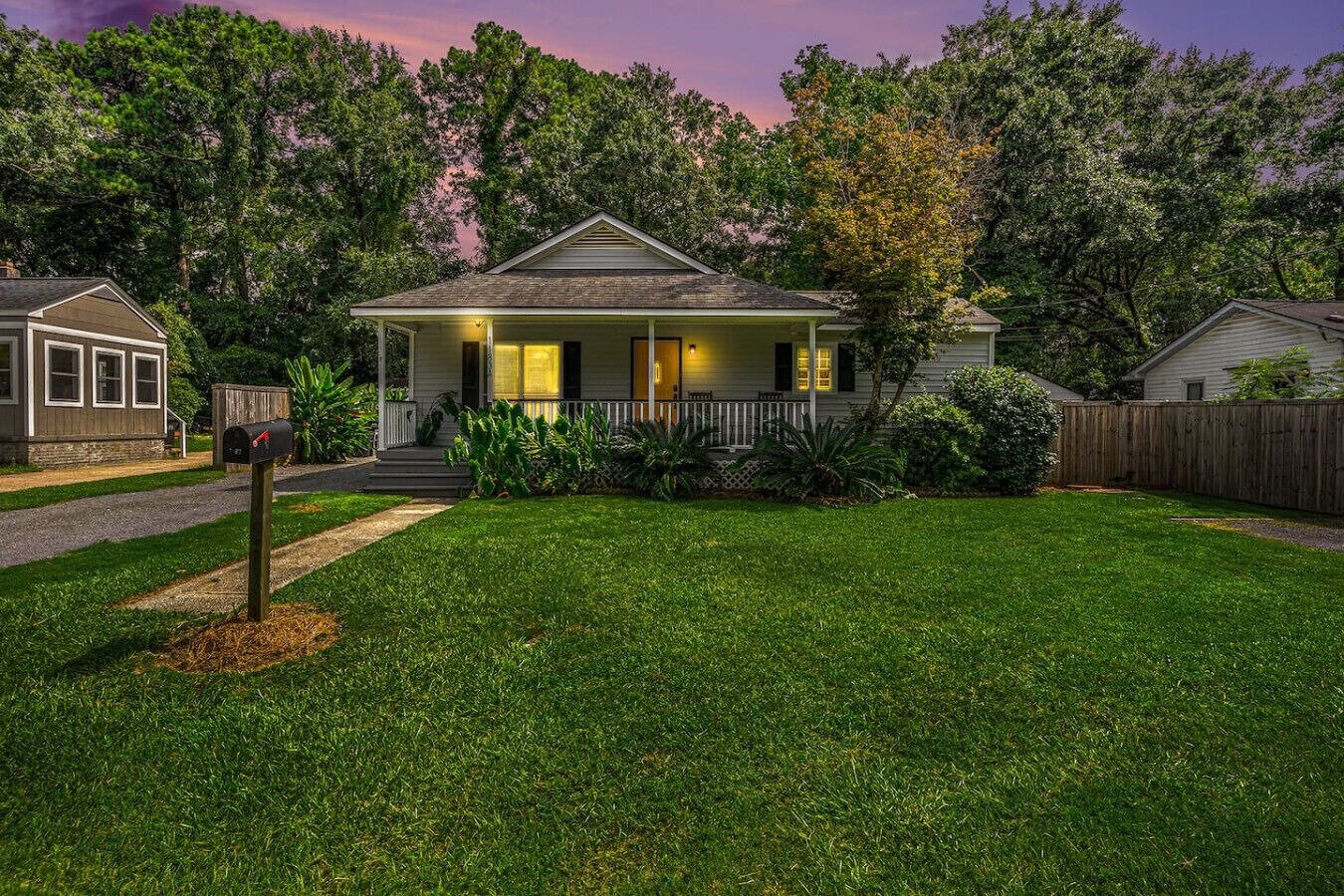 A residential house with a front porch, a mailbox, and a well-maintained lawn.