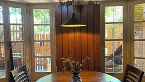 Una mesa de madera redonda para comer, con un florero de flores secas y sillas alrededor.