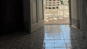 An open door leading to a balcony with a view of the sea, a potted plant, and a white chair. - The Arcade on the sea. Charming view at 3 minutes walk from the beach (Santa Marina Salina)
