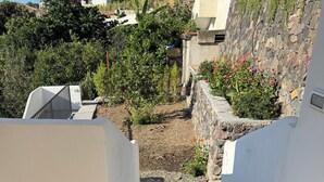 A staircase leading to a building with a stone wall and a garden with various plants and flowers. - The Arcade on the sea. Charming view at 3 minutes walk from the beach (Santa Marina Salina)