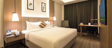 A hotel room with a large bed, bedside tables, a desk, and a TV.