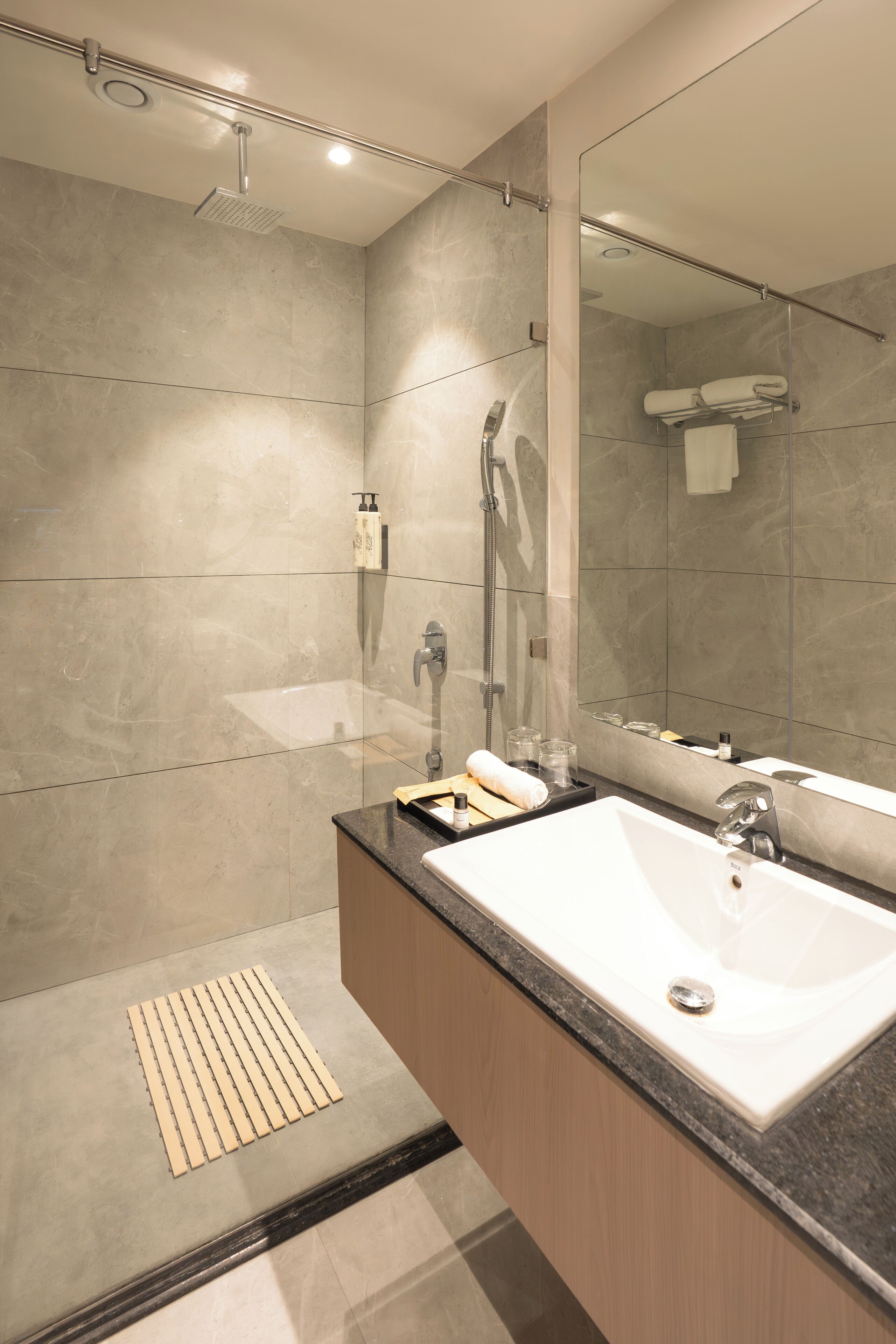 A modern bathroom with a large mirror, a sink, and a shower.