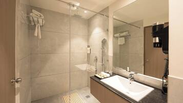 Un baño moderno con ducha de vidrio, un espejo grande y encimera de granito.
