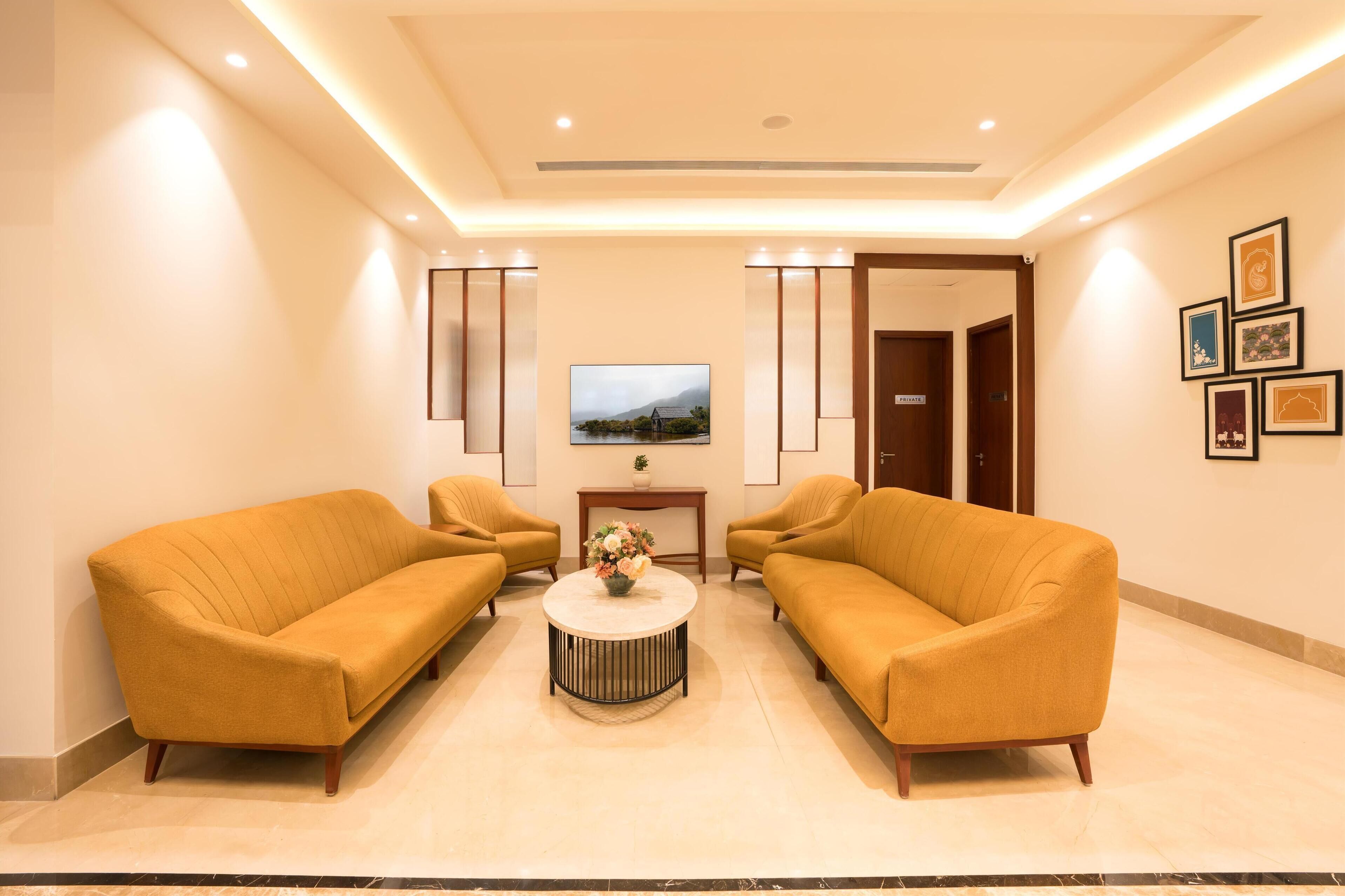 A lobby with two sofas, a coffee table, a TV, and framed pictures on the wall.