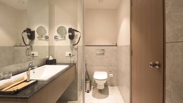 A modern bathroom with a large mirror, two hair dryers, a sink, and a toilet.