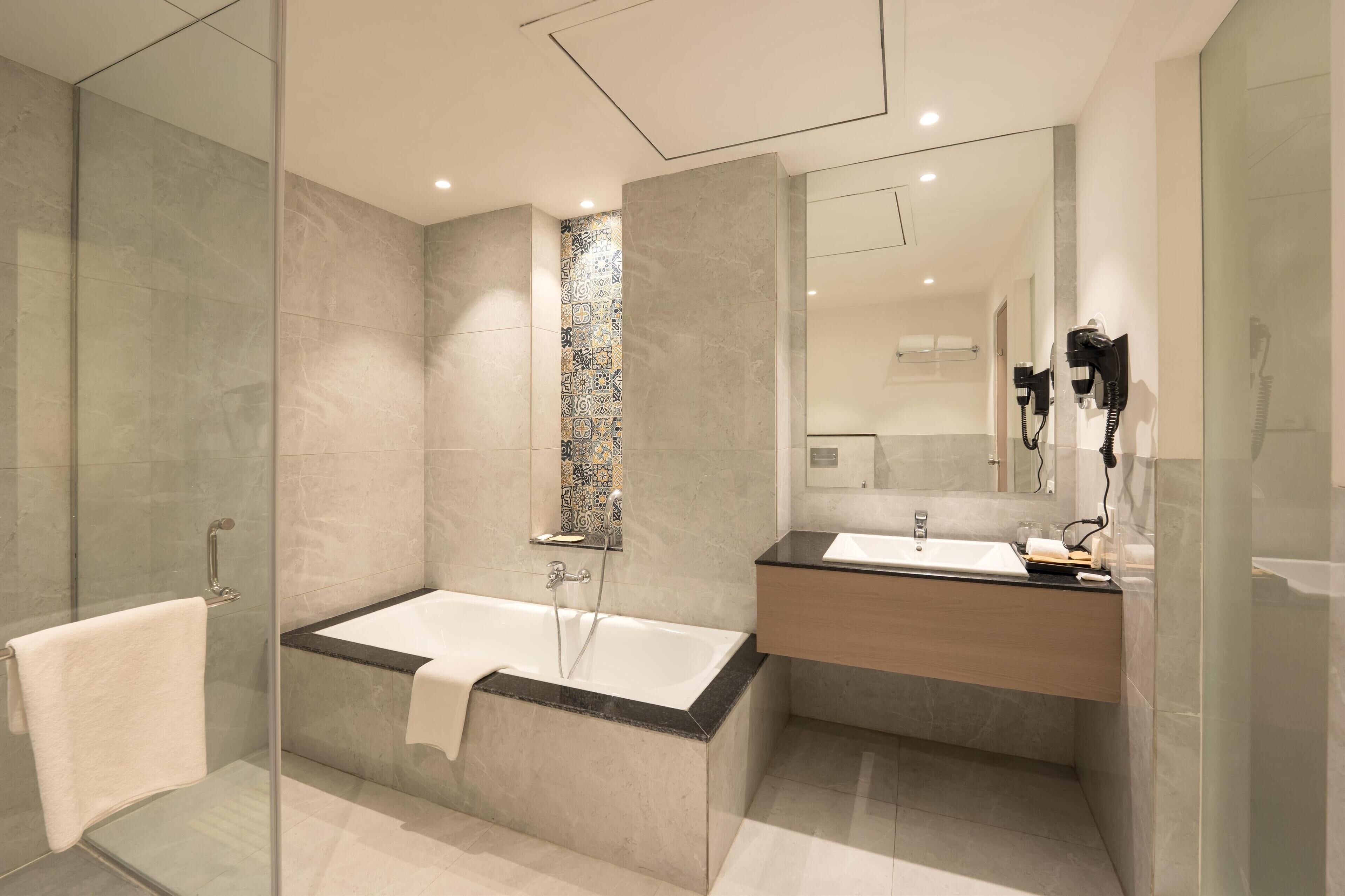 A modern bathroom with a glass-enclosed shower, a freestanding bathtub, and a vanity with a mirror.
