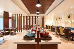 A modern dining area with a long counter, multiple tables, and chairs.