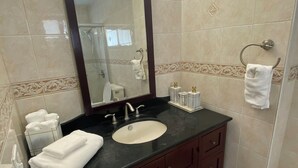 Un baño con lavabo, espejo, toallero y retrete.