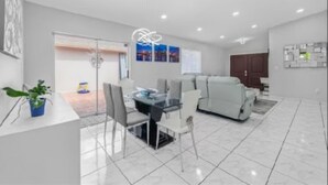 Una sala moderna con comedor, un conjunto de sofás y una planta en maceta.