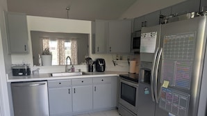 Een moderne keuken met grijze kastjes, een roestvrijstalen koelkast en een betegelde vloer.
