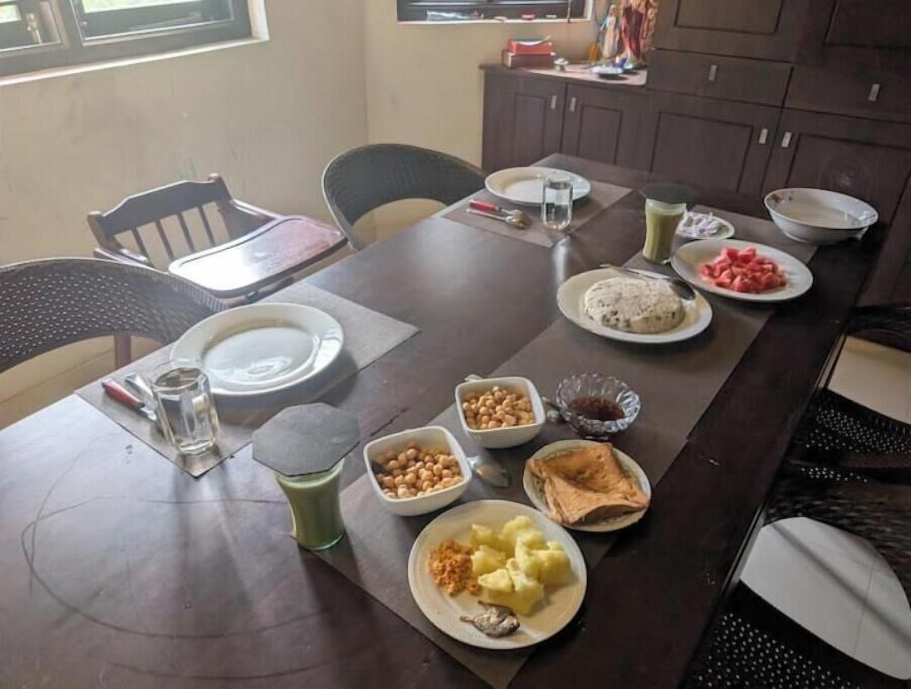 A dining table with various dishes, including a plate of mashed potatoes, a bowl of chickpeas, and a plate of watermelon.
