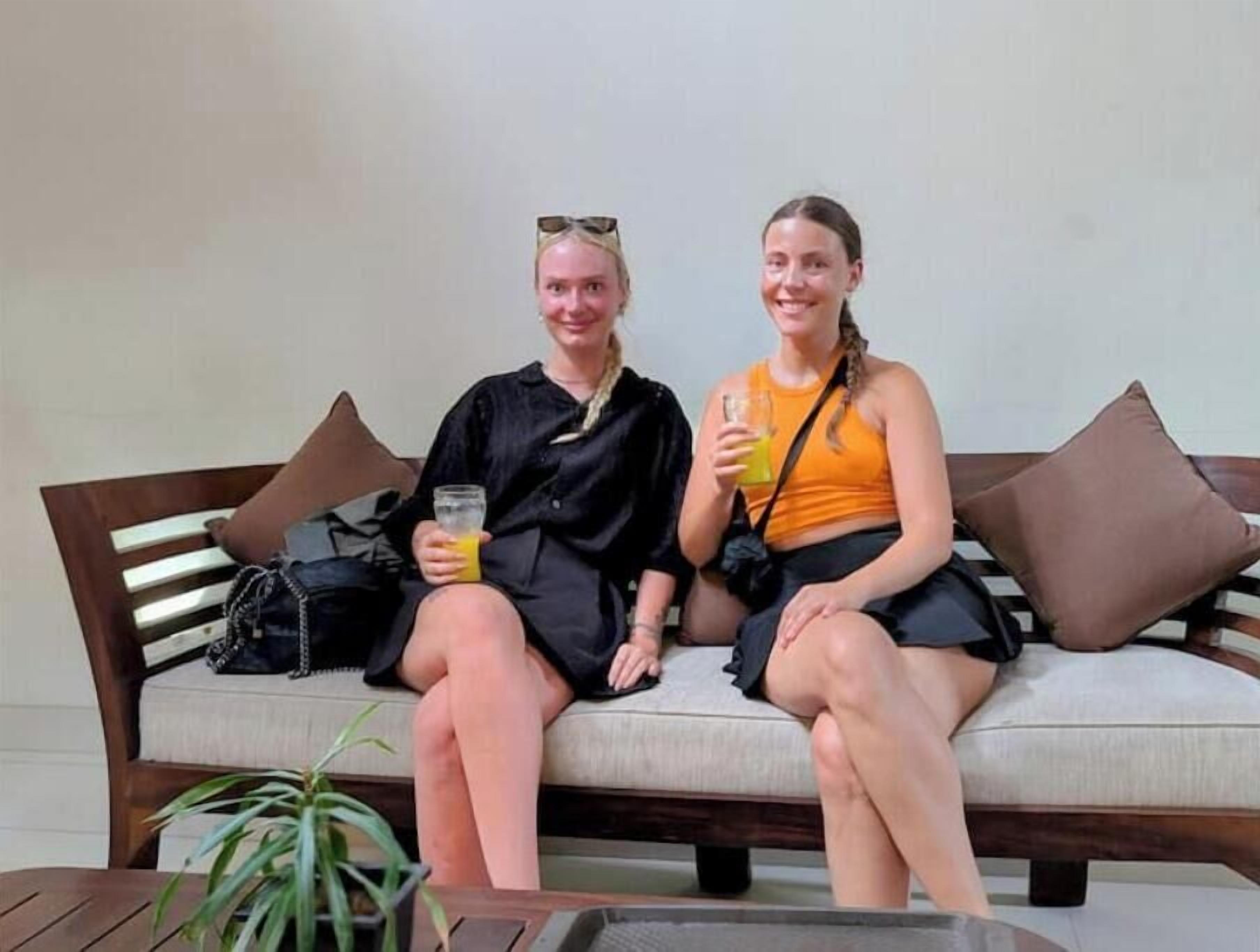 Two people sitting on a sofa with a plant in the foreground.