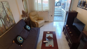Una sala de estar con sofá, mesa de centro, mueble para televisión y radiador.