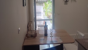 Un comedor con una mesa, sillas, una botella de vino y una copa. Se ve el exterior a través de una puerta.