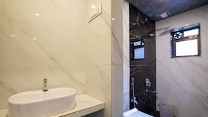 A bathroom with a white sink, a toilet, and a shower area. - Hotel Stayland Inn (Mumbai)