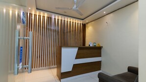 A reception area with a wooden slat wall, a reception desk, a ceiling fan, and a seating area. - Hotel Stayland Inn (Mumbai)