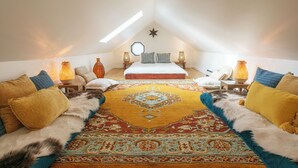 Un dormitorio acogedor en el ático con una cama grande, dos mesitas de noche, un adorno con forma de estrella y una alfombra estampada.