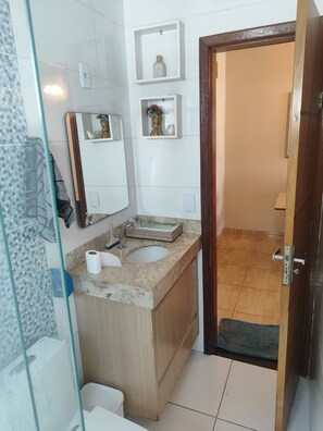 A bathroom with a sink, mirror, and shelves with toiletries. - High-end house with swimming pool and 3 bedrooms (Plano Diretor Sul Palmas)